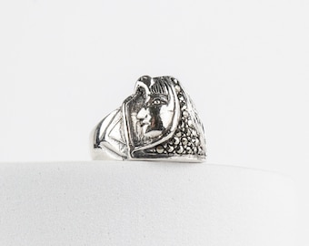 Könnte beinhalten: Ein silberner Ring mit einem Gesichtsdesign und einer schwarzen Steinfassung.