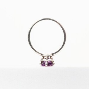 K&ouml;nnte beinhalten: Ein silberner Ring mit einem violetten Edelstein in einer Krappenfassung.