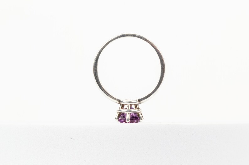 K&ouml;nnte beinhalten: Ein silberner Ring mit einem violetten Edelstein in einer Krappenfassung.