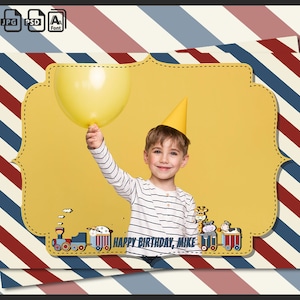 May include: A yellow birthday party photo booth backdrop with a red, white and blue striped pattern. A boy is holding a yellow balloon and wearing a yellow party hat. The backdrop has a yellow frame with a train and animals. The text "Happy Birthday, Mike" is on the backdrop.