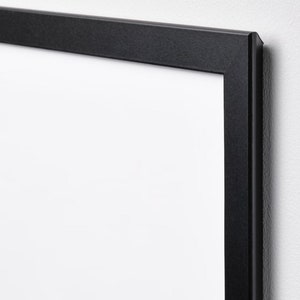 May include: A black picture frame with a white mat. The frame is made of wood and has a simple, modern design.