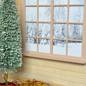 May include: A miniature Christmas scene with a small green flocked Christmas tree, two wrapped presents, one red and one gold, and a window with a view of snow-covered trees.