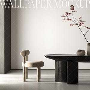 Puede incluir: Un interior de sala de estar minimalista con una mesa ovalada negra y una silla beige. Un jarrón con una rama seca y hojas rojas se encuentra sobre la mesa.