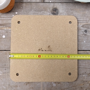 May include: A light brown square wooden board with rounded edges and four holes. The board is 20 inches long and has the word "Merenok" written on it.