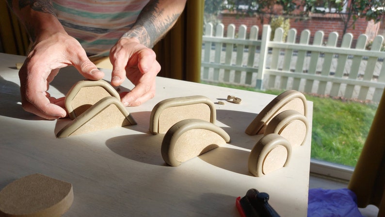 May include: A set of unfinished wooden arches and circles in various sizes, arranged on a light wood surface. The arches are made of a light brown wood and have a smooth, rounded edge. The circles are also made of light brown wood and have a smooth, flat surface. The arches and circles are arranged in a pattern that suggests they are part of a larger project.