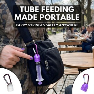Pu&ograve; includere: Borsa a tracolla nera con un porta siringa viola e una siringa attaccata. Il testo dell'immagine recita "TUBE FEEDING MADE PORTABLE" e "CARRY SYRINGES SAFELY ANYWHERE".