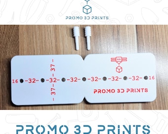 May include: White 3D printed parts with the text "PROMO 3D PRINTS". The parts include a measurement tool with numbers and a logo, along with two small white cylindrical pieces. The measurement tool has the numbers 16, 32, and 37.