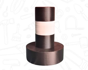 May include: A cylindrical object with a wide, circular base. The body is divided into three horizontal bands: dark brown at the top and bottom, and white in the middle. The object has a textured surface and appears to be made of a solid material.