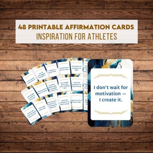 May include: A collection of 48 printable affirmation cards for athletes. The cards have inspirational quotes and are arranged on a wooden surface. The text "I don't wait for motivation - I create it" is visible.
