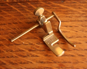 May include: A silver sewing machine foot with a metal rod and a knob. The foot is labeled "PEAF 41360".