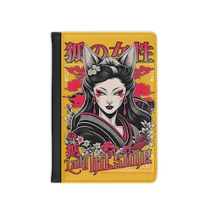 May include: A yellow passport holder featuring a stylized illustration of a woman with fox ears and makeup, with Japanese text. The design includes pink clouds and flowers, with the words "Lady Kitsune" in a stylized font. The holder has a black spine.