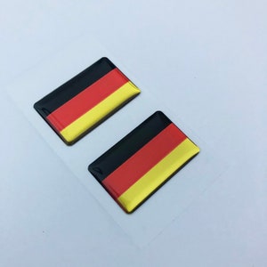 May include: Two black, red, and gold German flag stickers. The stickers are glossy and have a 3D effect.