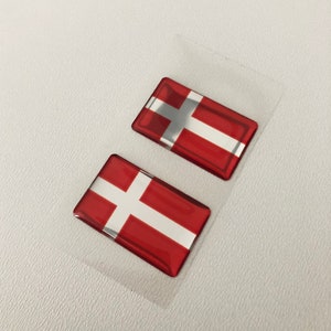 May include: Two red and white Danish flag stickers. The flags are glossy and have a 3D effect.