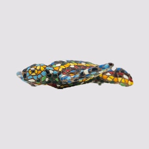 Op de afbeelding: Een mozaïek schildpadbeeldje met een kleurrijke, getextureerde schild. De schildpadschild bestaat uit kleine, onregelmatig gevormde stukjes in tinten blauw, geel, rood en groen. Het beeldje is een decoratief item.