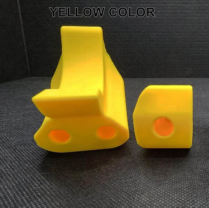 May include: Two yellow plastic toy blocks with rounded edges and holes. The blocks are shaped like a letter L and a rectangle.