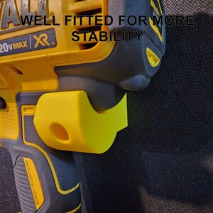 May include: A yellow and black DeWalt 20V MAX XR drill with a black and yellow plastic side handle. The text "WELL FITTED FOR MORE STABILITY" is printed on the drill.