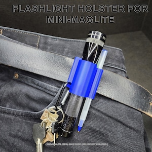 May include: A blue plastic flashlight holster with a carabiner clip, holding a black mini-maglite flashlight and a pen. The holster is attached to a black leather belt on a pair of blue jeans.