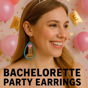 Puede incluir: Pendientes de despedida de soltera de madera con forma de lágrima azul, detalles rosas y las palabras "love squad". Los pendientes cuelgan de la oreja de una mujer. La imagen también incluye el texto "BACHELORETTE PARTY EARRINGS".