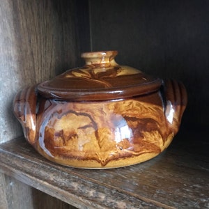May include: A brown ceramic casserole dish with a lid. The dish has a marbled glaze with brown and tan swirls.