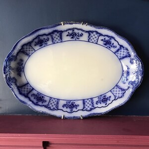 May include: A large oval blue and white porcelain serving platter with a floral design. The platter has a raised rim and a scalloped edge.