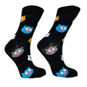 Könnte beinhalten: Ein Paar schwarze Socken mit einem bunten Katzenmuster. Die Socken zeigen blaue, graue, weiße und orange Katzen mit rosa Nasen.
