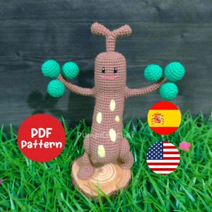 Könnte beinhalten: Häkelanleitung für eine braune und grüne Amigurumi-Baumfigur. Die Anleitung ist in Englisch und Spanisch verfügbar. Die Anleitung ist ein PDF-Download.