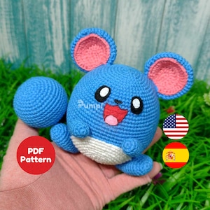 May include: Crochet pattern for a blue and pink amigurumi plush toy. The toy is shaped like a small mouse with large ears and a smiling face. The pattern is available in English and Spanish. PDF Pattern.