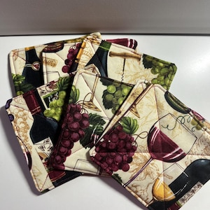 May include: Set of six quilted wine-themed fabric coasters. Each coaster features a different design with wine bottles, grapes, and wine glasses. The coasters are beige with red, green, and brown accents.