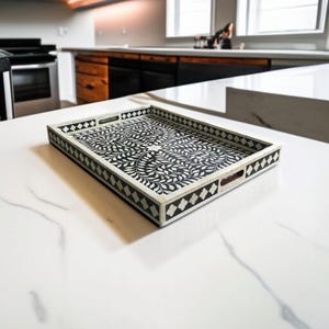 May include: A black and white tray with a floral design. The tray has a black border with white diamond shapes. The tray is made of bone inlay.