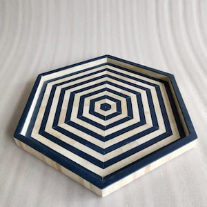 May include: A hexagonal tray with a blue and white striped pattern. The tray is made of bone inlay and has a dark blue border.
