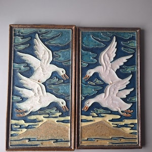 Två cloisonnéplattor från Porceleyne Fles som föreställer flygande gäss