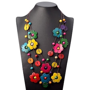 Peut inclure: Collier multi-rangs avec des breloques en bois en forme de fleurs de différentes couleurs, notamment jaune, rouge, bleu, vert et violet. Le collier est fait de cordon marron et comporte de petites perles rondes en bois.
