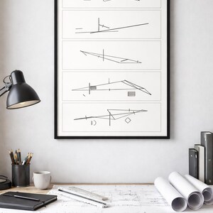 May include: A framed art print with five abstract architectural sketches in black lines on a white background. The artwork hangs above a wooden desk with a black lamp, pencils, a mug, and rolled blueprints. The desk is made of wood.