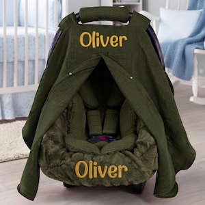 Peut inclure: Une housse de siège auto vert olive dotée d'une capote en tissu texturé et d'une base en peluche. Le prénom Oliver est brodé en fil jaune sur la partie supérieure de la capote et sur la partie avant inférieure de la housse de siège auto.