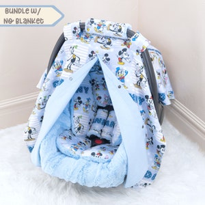May include: A blue baby car seat cover featuring a Mickey Mouse and friends print. The cover has a hood that can be pulled up to shield the baby from the sun. The cover is made from soft, breathable fabric and is machine washable.