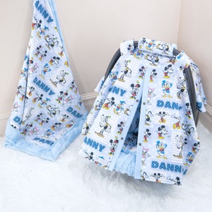 May include: A blue and white baby car seat cover featuring a Mickey Mouse and friends print. The cover has the name "Danny" printed on it. The cover is made of soft, comfortable fabric and is ideal for protecting your car seat from spills and messes.