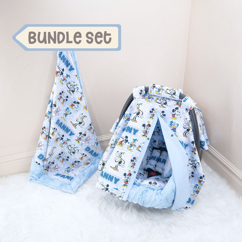 May include: A blue and white baby car seat cover with a Mickey Mouse print and the name "Danny" on it. The cover is part of a bundle set that also includes a matching blanket.