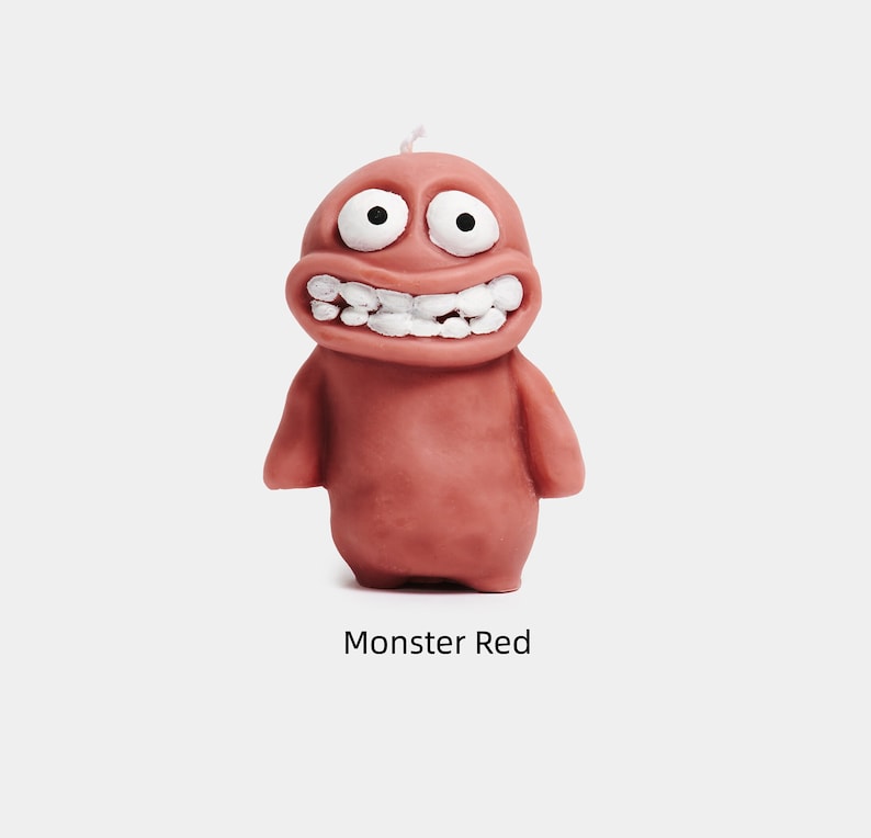 May include: A red monster candle with a wide smile and large eyes. The candle is made of wax and has a simple design.