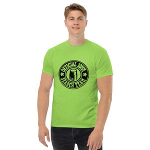 May include: A lime green t-shirt featuring a black circular graphic with the text "OFFICIAL 10MM SEARCH TEAM" and a graphic of a cylinder with the number 10 inside. The shirt is short-sleeved and made of a soft material.