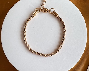 May include: A gold-toned rope chain bracelet with a lobster clasp closure.