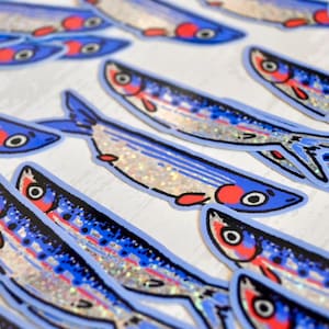 May include: A collection of blue and silver glitter fish stickers. The fish have red and white details on their eyes and mouths.