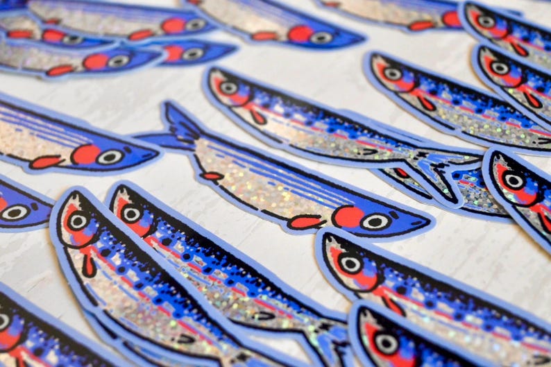 May include: A collection of blue and silver glitter fish stickers. The fish have red and white details on their eyes and mouths.