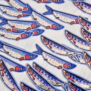 May include: A collection of blue and white fish stickers with glitter accents. The fish are arranged in rows and are all facing the same direction.