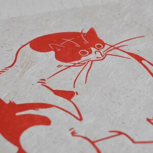 May include: Red line drawing of a cat on a white background. The cat is curled up in a ball with its tail wrapped around its body. The cat's eyes are closed and its mouth is slightly open.
