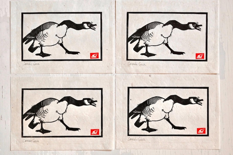May include: Four black and white prints of Canada geese with their necks stretched out. Each print is framed in a black border and has the text "Canada Goose" at the bottom.