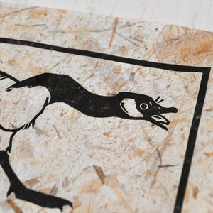 May include: Black and white illustration of a goose with its head turned to the side, printed on a textured paper background.