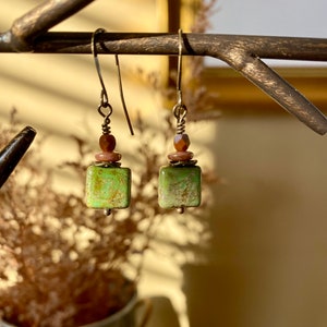 May include: A pair of green and brown dangle earrings with square green stones and brown beads.