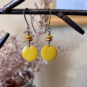 May include: A pair of yellow ceramic disc earrings with gold beads and silver hooks.