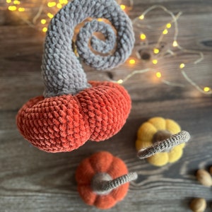 May include: Three crocheted pumpkins in orange, yellow, and gray. The pumpkins are made with a soft, fuzzy yarn and have a rustic, handmade look.