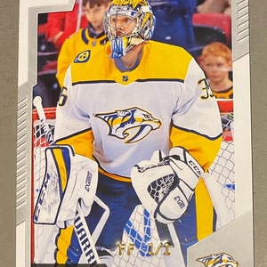 Może przedstawiać: Karta hokejowa z Pekką Rinne, bramkarzem Nashville Predators. Karta ma białą obwódkę z logo O-Pee-Chee. Rinne ma na sobie żółtą, białą i niebieską koszulkę Predators i maskę bramkarską.
